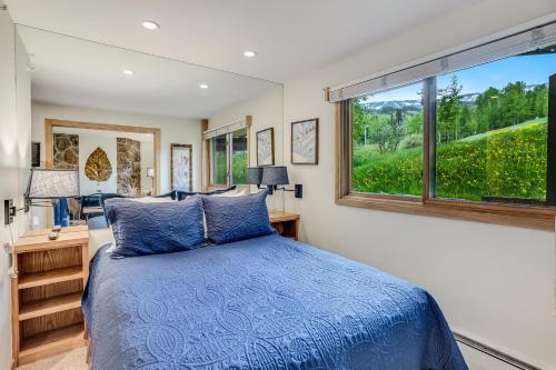 sypialnia z niebieskim łóżkiem i oknem w obiekcie Laurelwood Condominiums 405 w mieście Snowmass Village