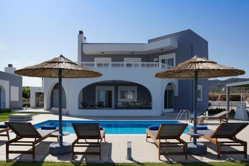 una villa con piscina, sedie e ombrelloni di Villa Arco Bianco a Afantou