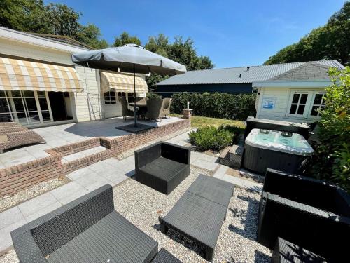 a patio with a table and an umbrella and a pool at Modern Holiday Home in Kaatsheuvel with bubble bath in Kaatsheuvel