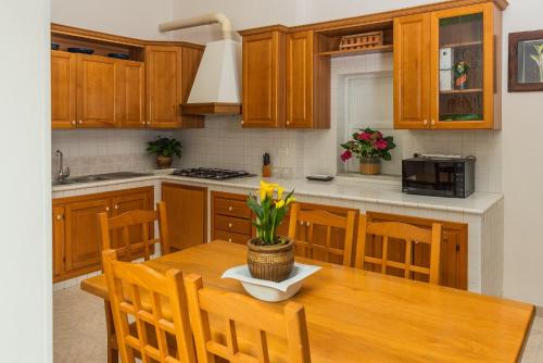 a kitchen with wooden cabinets and a wooden table with flowers at VILLA MAVI in Formia