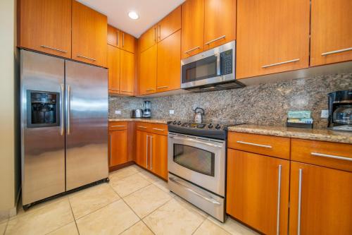 a kitchen with wooden cabinets and stainless steel appliances at Kapalua Villas Maui in Lahaina