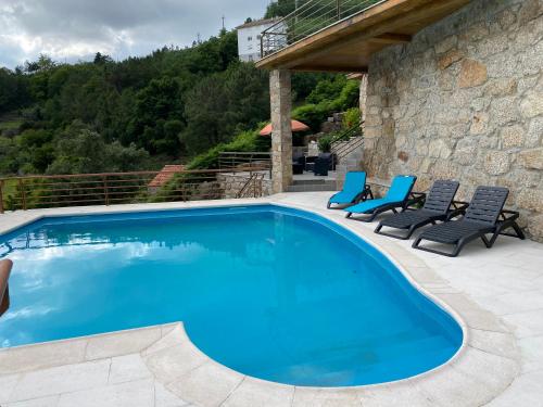 einen Pool mit Stühlen und ein Haus in der Unterkunft Chão da Relva - Turismo & Natureza in Loriga