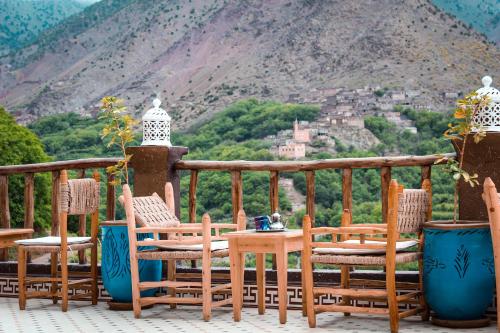 eine Terrasse mit Stühlen und einem Tisch mit Bergblick in der Unterkunft da housa hostel in Tahliouine