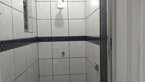 a white tiled bathroom with a urinal on the wall at Hotel Faf's in Sao Paulo