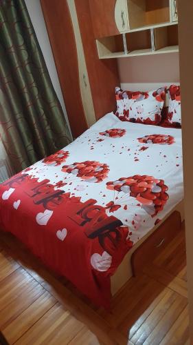uma cama com um edredão vermelho e branco com corações em Apartamentul Oaspetilor em Slatina