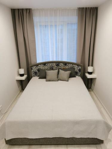 a bedroom with a large white bed with a window at Home 4 YOU - self check-in in Ventspils