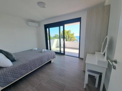 a bedroom with a bed and a desk with a view of the ocean at Villa Leptirić in Vir