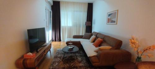 a living room with a couch and a tv at South Side Apartment in Podgorica