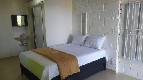 uma cama num quarto com uma parede de tijolos brancos em FINCA COOMPAB em El Peñol
