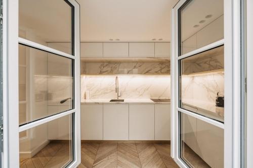 a kitchen with white cabinets and glass doors at HIGHSTAY - Luxury Serviced Apartments - Place Vendôme in Paris