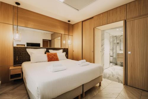 um quarto com uma grande cama branca e uma casa de banho em HIGHSTAY - Luxury Serviced Apartments - Place Vendôme em Paris