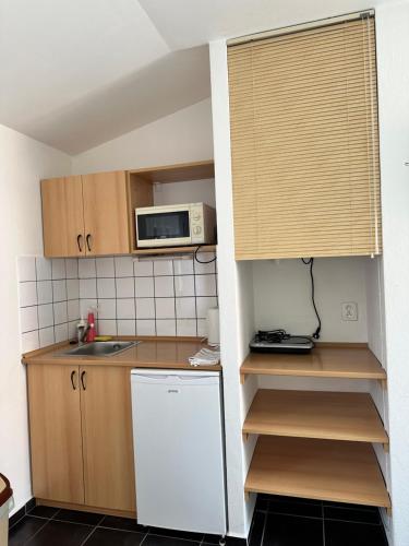 Il comprend une petite cuisine équipée d'un réfrigérateur blanc et d'un four micro-ondes. dans l'établissement Penzion, vinný sklep a café Bárta, à Mikulov