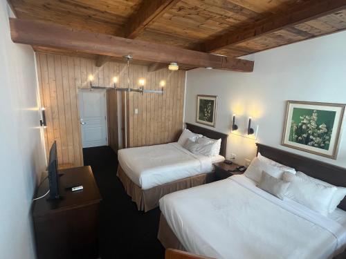 Habitación de hotel con 2 camas y TV en Hôtel La Côte Surprise, en Percé