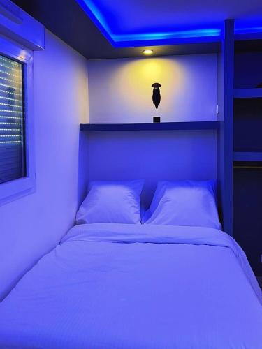 a bedroom with a white bed with a blue light at charmant studio in Vaulx-en-Velin