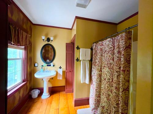 a yellow bathroom with a sink and a mirror at Admiral Peary Inn in Fryeburg