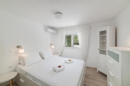 a white bedroom with a white bed and a window at Cozy Cottage in Istron