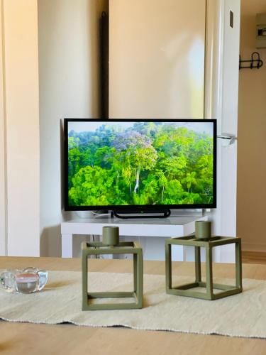 a flat screen tv sitting in a living room with two tables at Scandinavian Apartment Hotel - Prison Museum 2 - one room apartment in Horsens