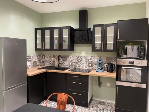 une cuisine avec des armoires noires et des appareils en acier inoxydable dans l'établissement duplex dans le triangle d'or, à Compiègne