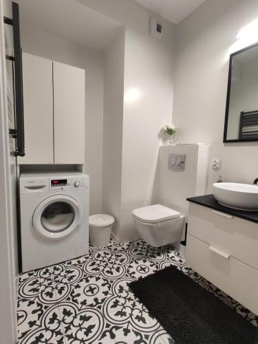biała łazienka z pralką i umywalką w obiekcie Nowoczesny apartament dla par w Krakowie