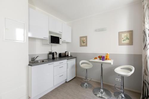 una pequeña cocina con armarios blancos y taburetes en Elegant studio proche Palais des Festivals, en Cannes