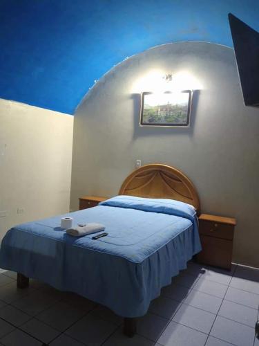 a bedroom with a bed with a blue blanket and a window at Hostal Flores in Arequipa