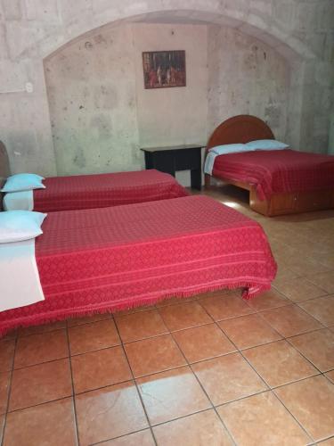 twee bedden in een kamer met rode lakens erop bij hostal flores in Arequipa