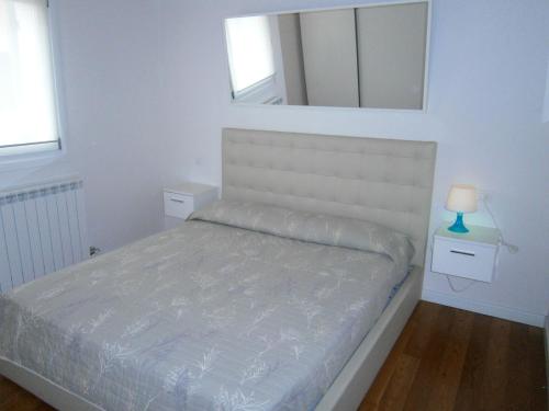 - une chambre blanche avec un lit et un miroir dans l'établissement Casa Incanto - Agenzia Cocal, à Caorle