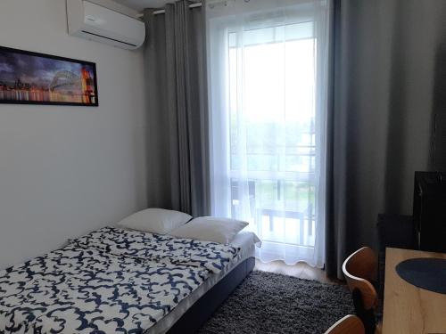 a bedroom with a bed in front of a window at Apartament Zachód in Warsaw