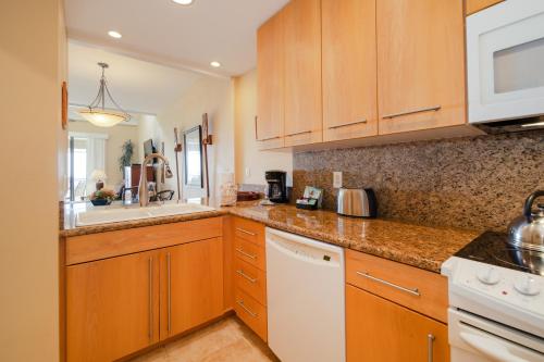 a kitchen with wooden cabinets and a white dishwasher at Kapalua Villas Maui in Lahaina