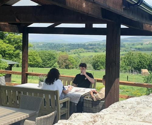 a man and two women sitting at a table on a patio at The Safari Tent @ The Old Forge Glamping in Tullow