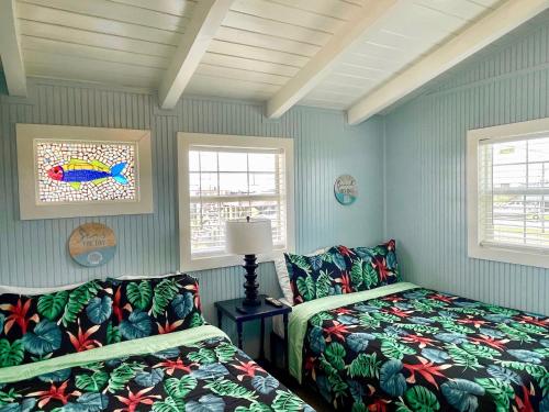 a bedroom with two beds and two windows at Blue Dolphin Inn and Cottages in Grand Isle