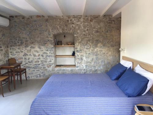 a bedroom with a blue bed and a stone wall at Skalina House in Tivat