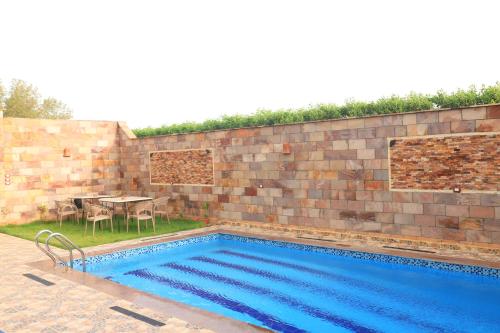 a swimming pool with a table and a brick wall at Royal Mountain in Luxor