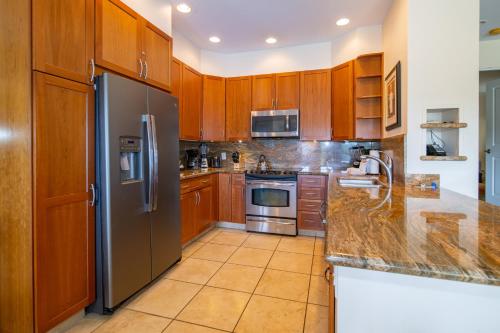 a kitchen with wooden cabinets and a stainless steel refrigerator at Kapalua Villas Maui in Lahaina