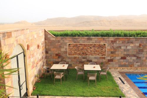 a patio with tables and chairs next to a brick wall at Royal Mountain in Luxor