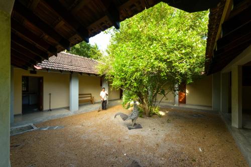 a person standing next to a tree in a courtyard at Mannankulam Villa in Akkaraipattu