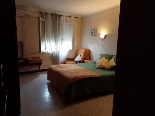 1 dormitorio con 1 cama, 1 silla y 1 ventana en Petite maison de village, en Ria