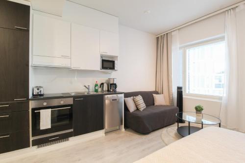 uma cozinha e sala de estar com um sofá e uma mesa em City Apartment Tornitupa em Kuopio