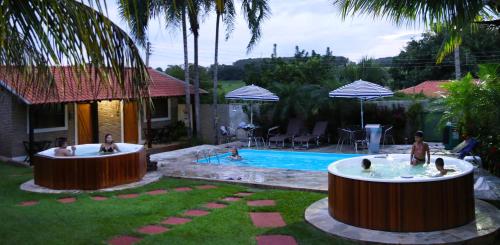 a pool with two hot tubs in a yard at Monte Carlo Pousada in Olímpia