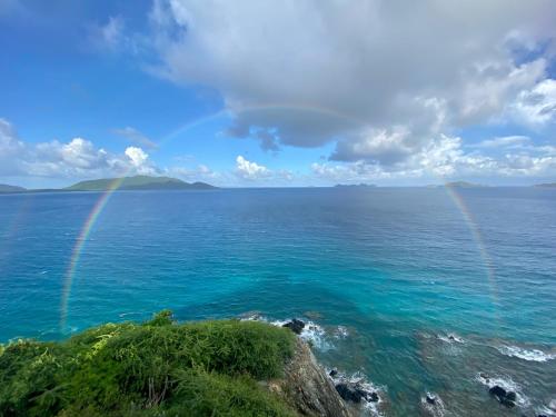 two rainbows over the ocean with a rocky shore at The Aerial, BVI All-Inclusive Private Island in Tortola Island