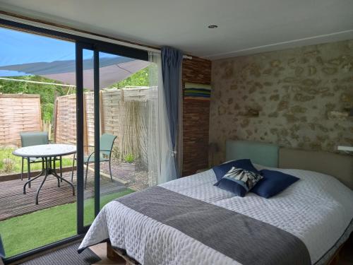 een slaapkamer met een bed en een balkon met een tafel bij Gîte de la Poterie "vue sur Loire" in Mosnes