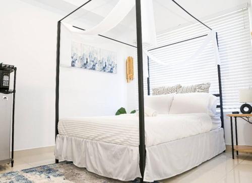a bedroom with a canopy bed with white sheets at Insta Worthy Oasis in Homestead