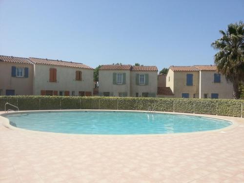a swimming pool in front of some houses at Villa à deux pas de la cité médiévale dans une résidence très calme in Aigues-Mortes