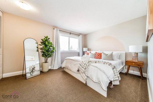 a bedroom with a white bed and a mirror at Cozy 3BD w/AC, Patio, Theatre Room, 15 min to DT in Edmonton