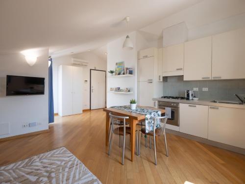 eine Küche mit weißen Schränken sowie einem Tisch und Stühlen in der Unterkunft Appartamento Pesco "A Casa Felice" in Pietra Ligure
