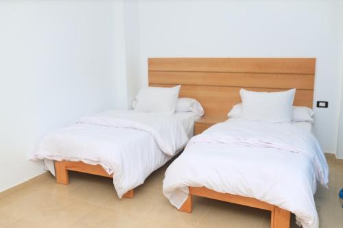 two beds with white blankets and pillows in a room at Royal Mountain in Luxor