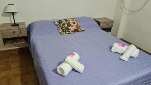 Una cama morada con toallas encima. en Italia apart departamentos por día con cochera opcional en Corrientes