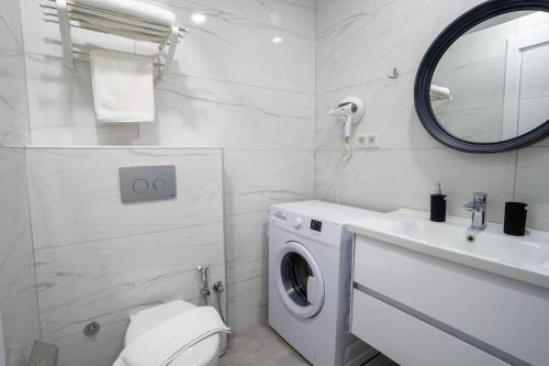 a white bathroom with a washing machine and a sink at Shah Residence Hotel in Bostancı