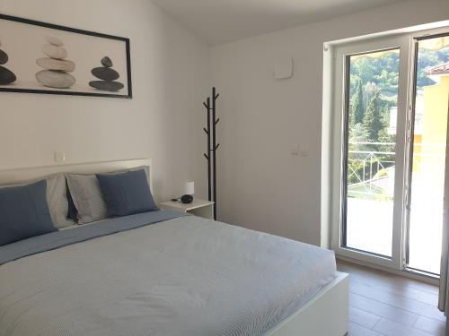 a white bedroom with a large bed and a window at Seafront Apartment Strunjan in Strunjan