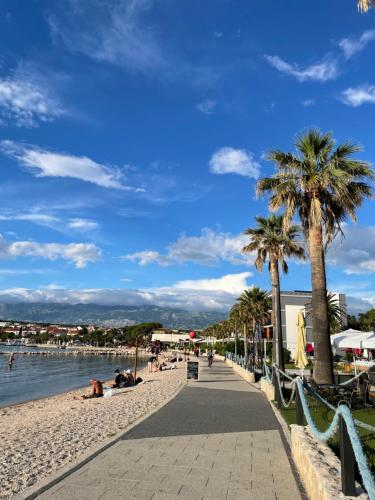 a beach with palm trees and people laying on the sand at Luxury apartment Golden Mint in Novalja